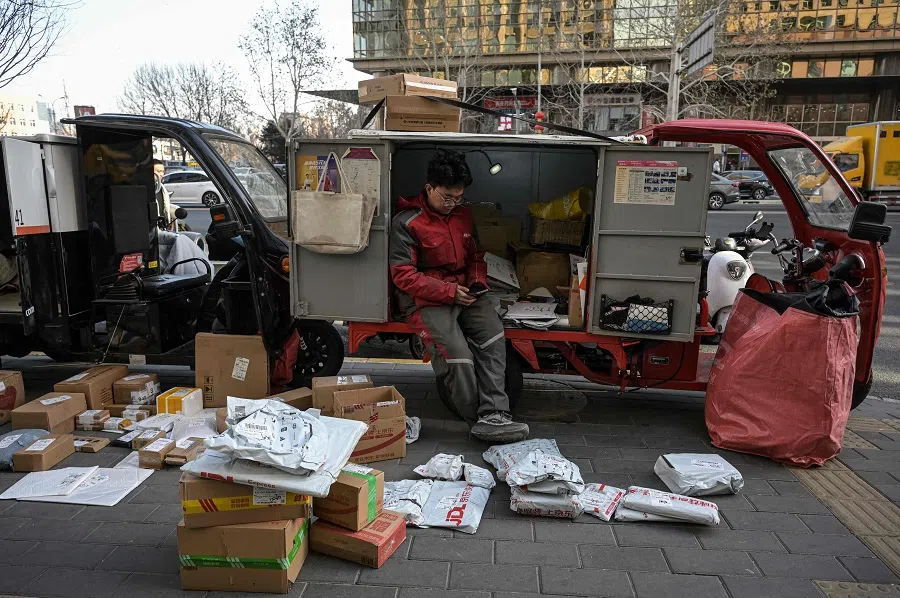 A delivery worker sits on a delivery vehicle along a street in Beijing, China, on 17 January 2025. (Jade Gao/AFP)