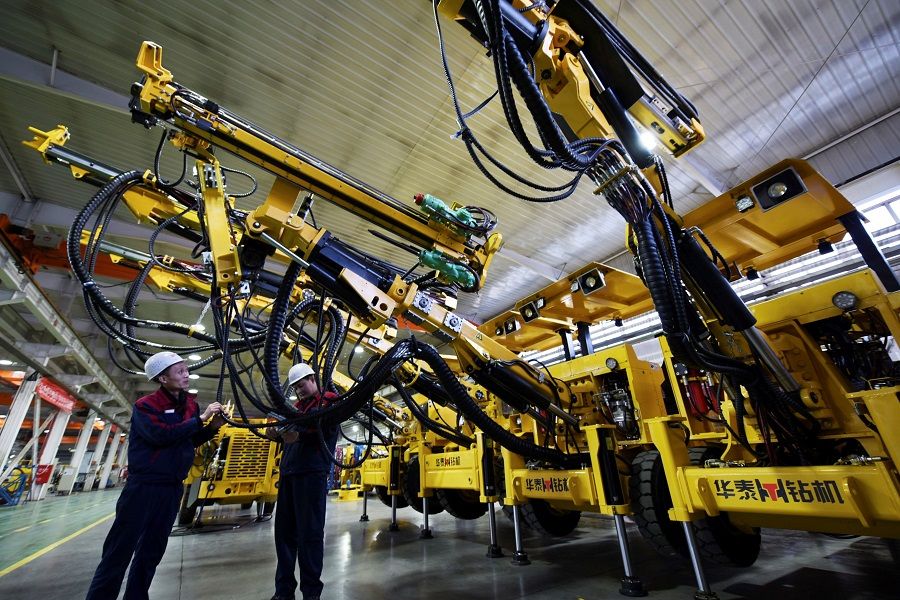 This photo taken on 19 December 2020 shows employees working on a drilling machine assembly line at a factory in Zhangjiakou, Hebei province, China. (STR/AFP)