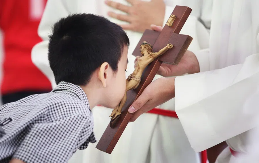 A boy kisses the cross in veneration during a Good Friday service.