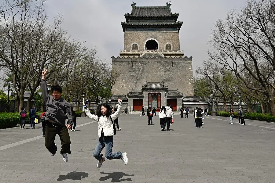 People jump as they pose for a picture on the Bell Tower esplanade in Beijing on 13 April 2025. (Pedro Pardo/AFP)