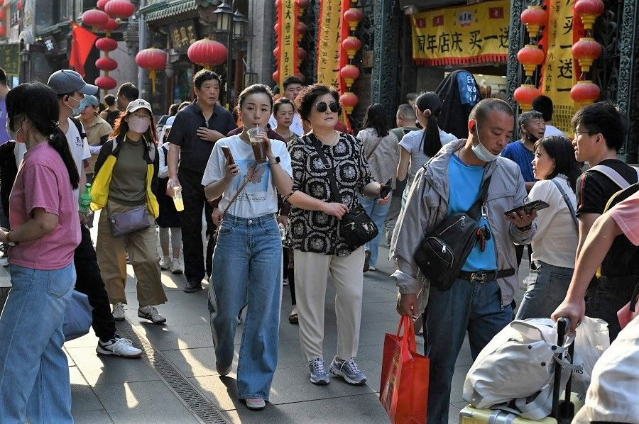 People walk through a traditional shopping street in the Qianmen area of Beijing, China, on 3 May 2023. (Greg Baker/AFP)