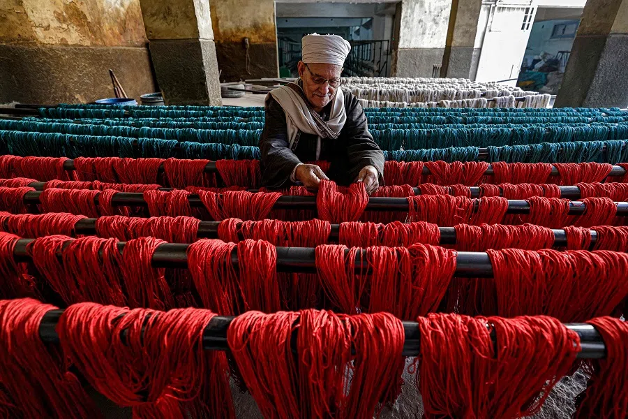 In this picture taken on 20 February 2023, dyed threads are hung out to dry at the Kahhal Looms handmade rugs workshop in the Basateen district of Cairo, Egypt. (Khaled Desouki/AFP)