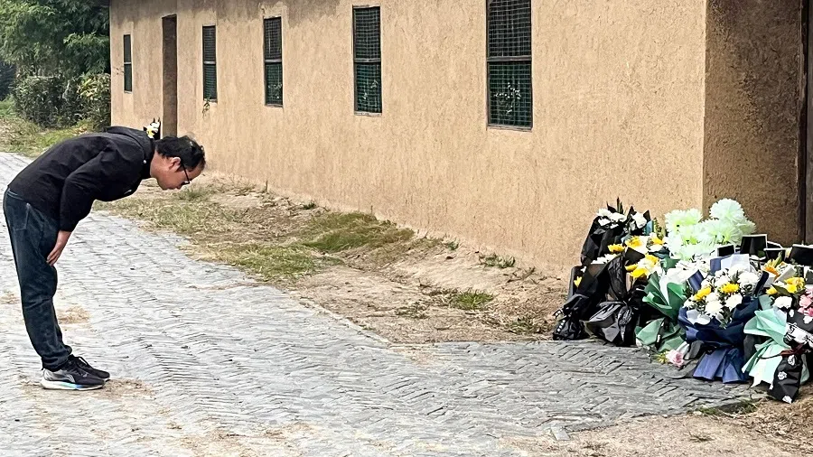A man bows in front of the former house of former Chinese Premier Li Keqiang in Dingyuan county, Chuzhou city, Anhui province, China, on 27 October 2023. (Rebecca Bailey/AFP)