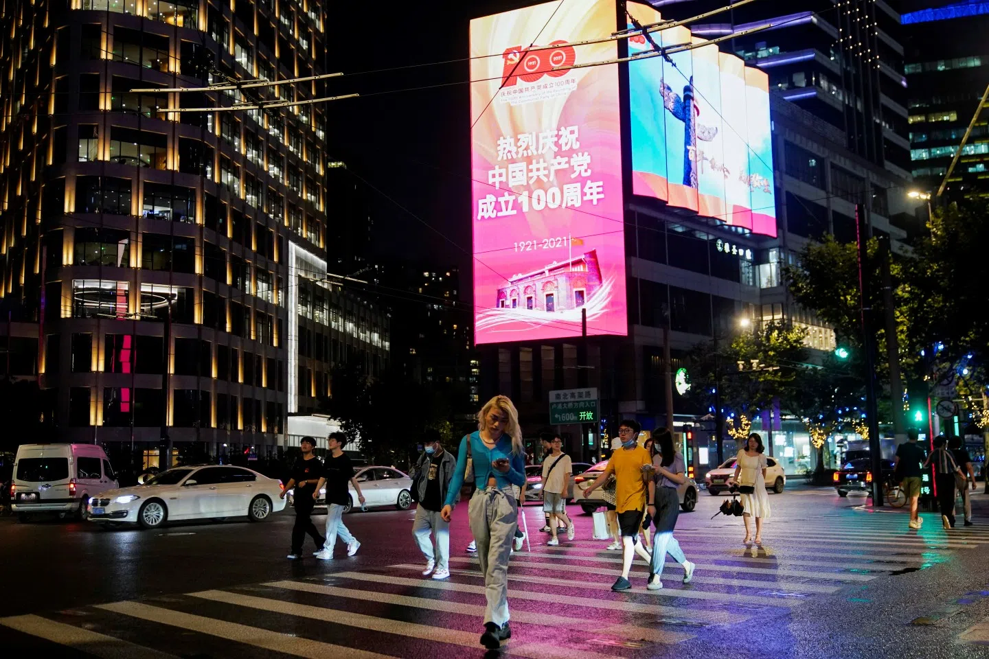 People walk on a street in front of a screen marking the 100th founding anniversary of the Communist Party of China, in Shanghai, China, 15 June 2021. (Aly Song/Reuters)