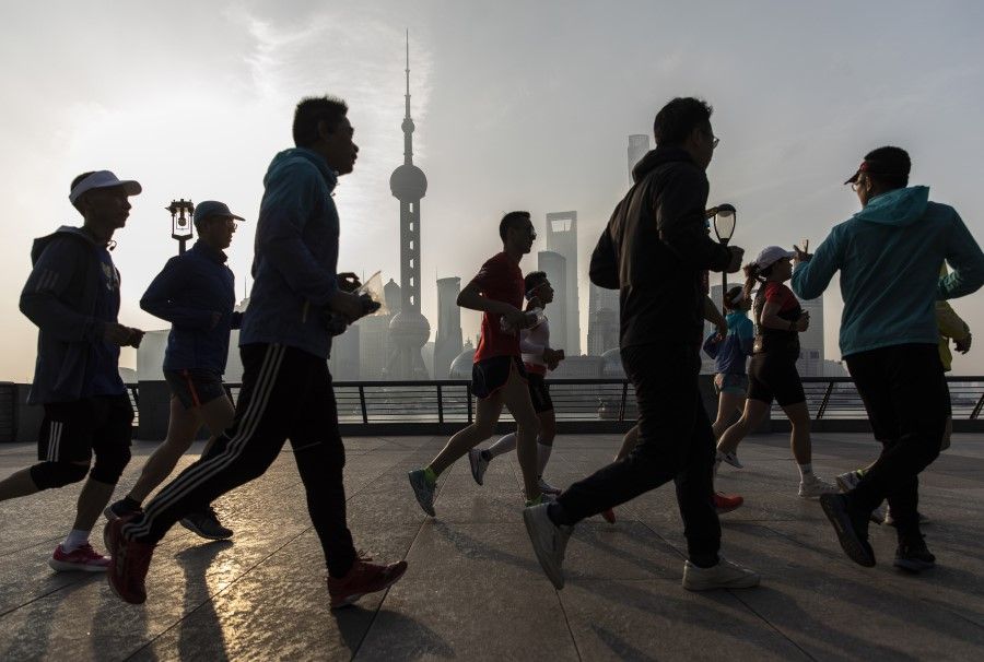 Joggers run along the Bund as the Lujiazui Financial District stands in the background in Shanghai, China, 10 April 2021. (Qilai Shen/Bloomberg)
