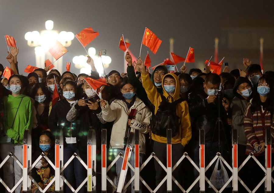 People wearing face masks wave China flags during a flag-raising ceremony at Tiananmen Square on National Day to mark the 71st anniversary of the founding of People's Republic of China, in Beijing, China, 1 October 2020. (Carlos Garcia Rawlins/Reuters)