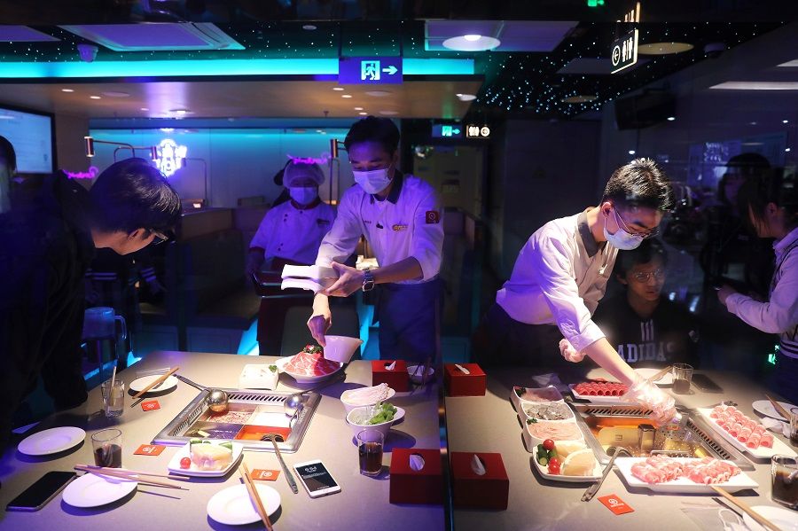 Waiters serve customers at a Haidilao hotpot restaurant in Beijing, China, 11 October 2021. (Tingshu Wang/Reuters)