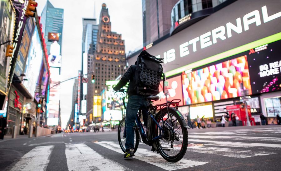 A food delivery man crosses the street in Times Square in Manhattan on 17 March 2020 in New York City. The coronavirus outbreak has transformed the US virtually overnight from a place of boundless consumerism to one suddenly constrained by nesting and social distancing. (Johannes Eisele/AFP)