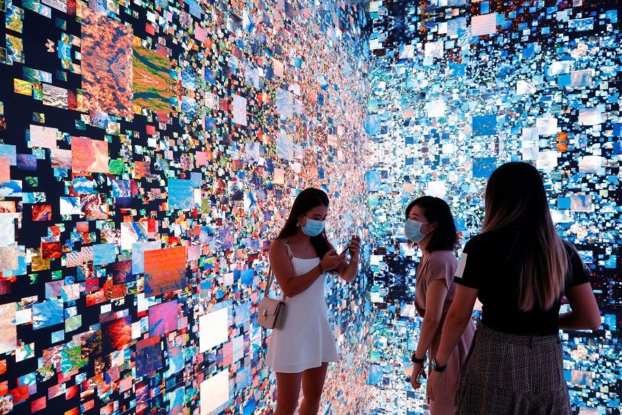 Visitors are pictured in front of an immersive art installation titled "Machine Hallucinations - Space: Metaverse" by media artist Refik Anadol, which will be converted into NFT and auctioned online at Sotheby's, at the Digital Art Fair, in Hong Kong, China, on 30 September 2021. (Tyrone Siu/Reuters)