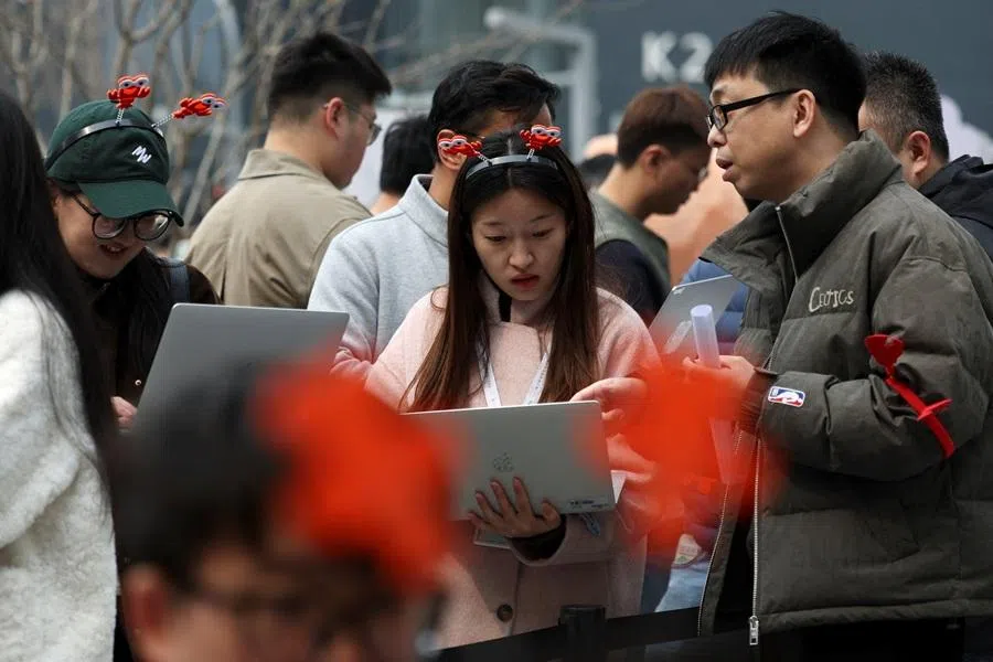 Participants hold their laptops as they line up to install and set up OpenClaw, an open-source AI agent, outside the Baidu offices in Beijing, China, 17 March 2026.