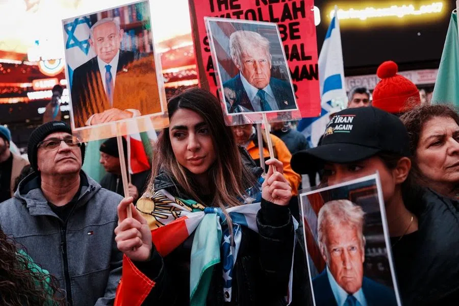 A protester holds images of US President Donald Trump and Israeli Prime Minister Benjamin Netanyahu in Times Square during a demonstration against the Iranian government, New York City, US, on 15 March 2026.