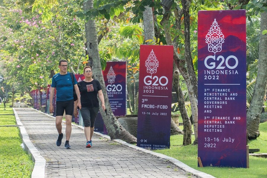 Foreign tourists walk past banners near the main venue of the G20 Finance Ministers and Central Bank Governors Meeting in Nusa Dua, Bali, Indonesia, 14 July 2022. (Made Nagi/Pool via Reuters)