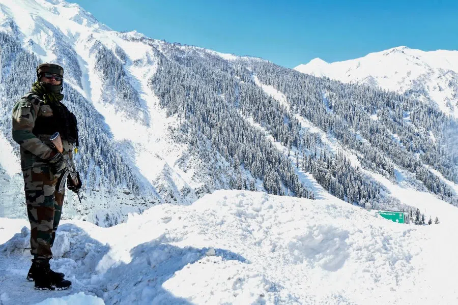 An Indian army soldier stands on a snow-covered road near Zojila mountain pass that connects Srinagar to the union territory of Ladakh, bordering China on 28 February 2021. (Tauseef Mustafa/AFP)