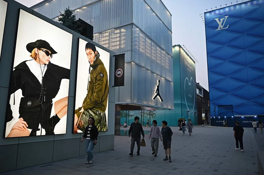 People walk outside a shopping mall in Beijing on 21 May 2025.