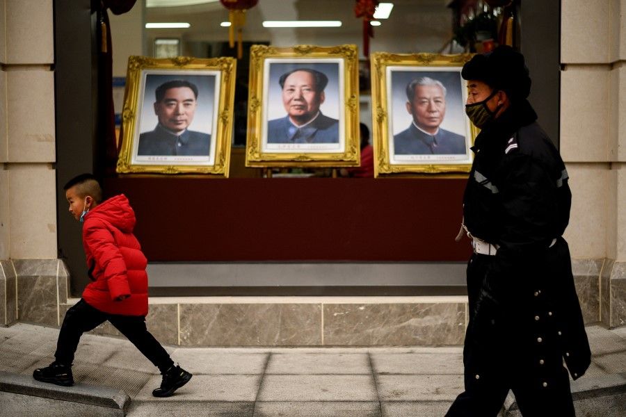 People walk past portraits of Chinese leaders displayed at a shop along Wangfujing shopping street in Beijing on 14 February 2021. (Noel Celis/AFP)
