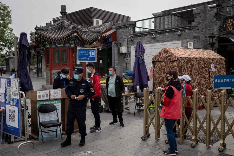 Security guards and officials wearing face masks as a preventive measure against the COVID-19 coronavirus secure a gate at the entrance of a residential street that can only be accessed by residents in Beijing, 4 May 2020. (Nicolas Asfouri/AFP)