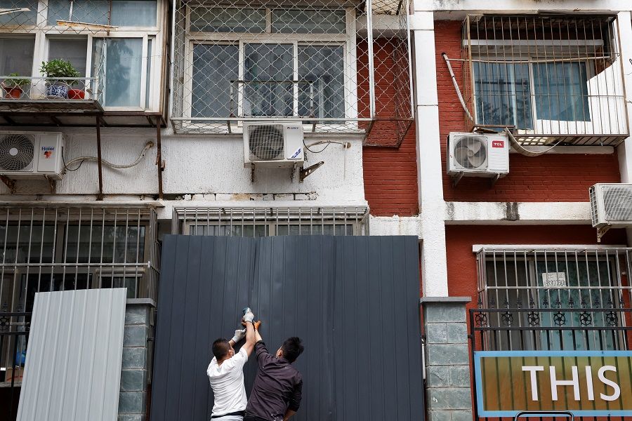Workers install a barricade around a residential area under lockdown, amid the Covid-19 outbreak in Beijing, China, 10 June 2022. (Carlos Garcia Rawlins/Reuters)