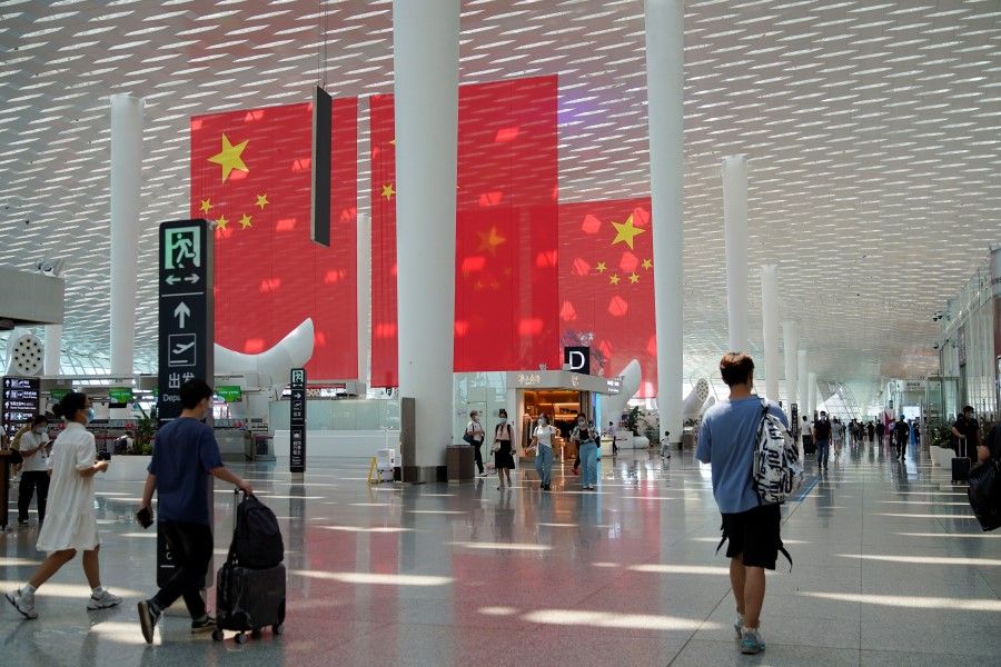 Travellers walk past Chinese flags ahead of China's National Day and Golden Week holiday, at Shenzhen Baoan International Airport in Shenzhen, Guangdong province, China 30 September 2021. (Aly Song/Reuters)