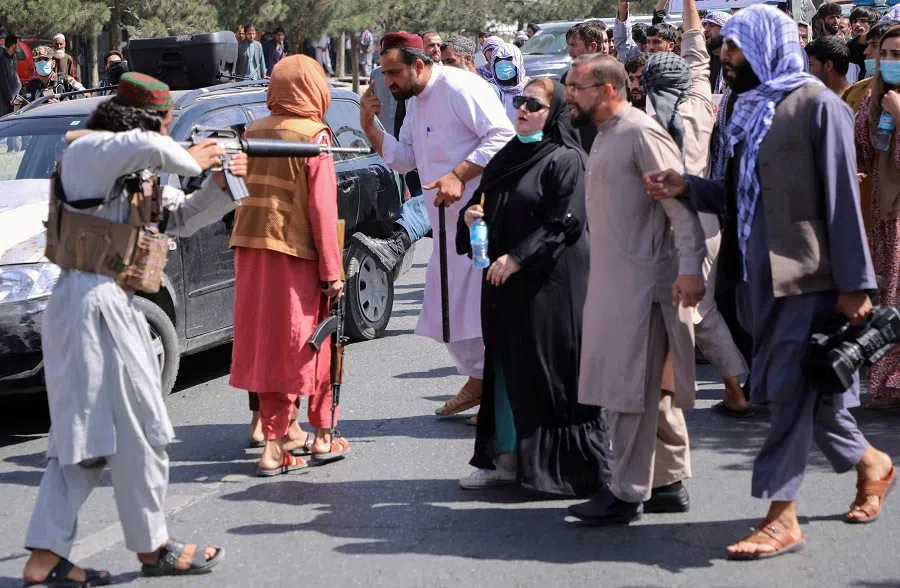 A member of the Taliban forces points his gun at protesters, as Afghan demonstrators shout slogans during an anti-Pakistan protest, near the Pakistan embassy in Kabul, Afghanistan, 7 September 2021. (Stringer/Reuters)