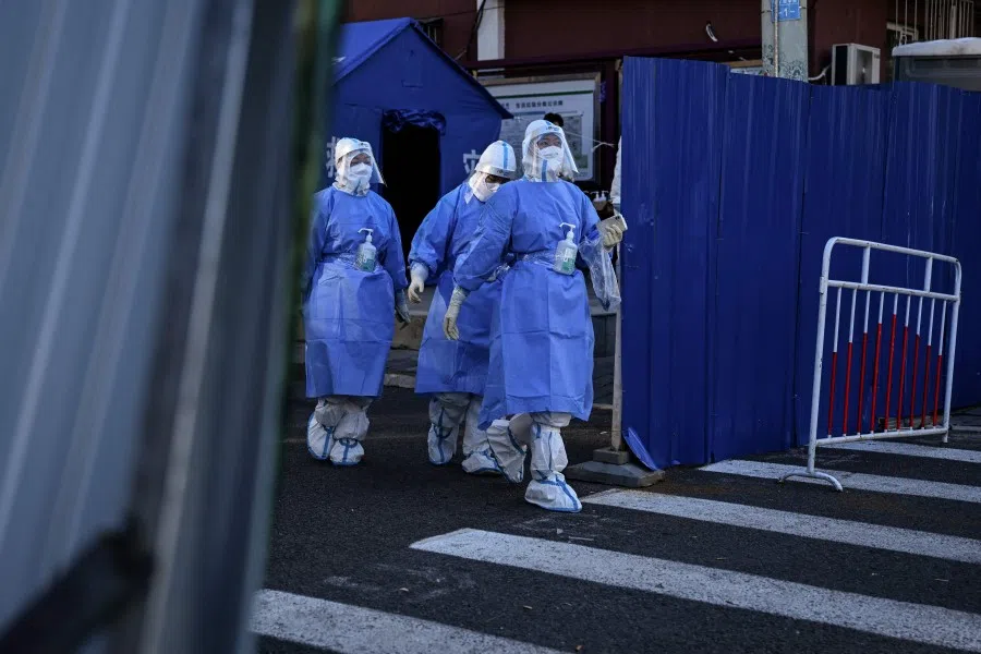 Health workers are seen at a residential area under lockdown due to Covid-19 restrictions in Beijing on 13 November 2022. (Noel Celis/AFP)