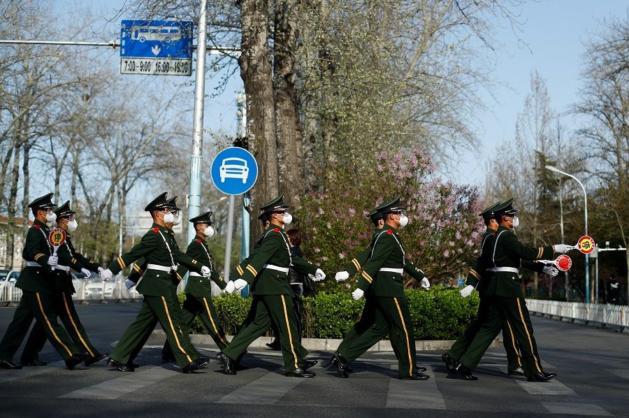 Paramilitary police officers wearing protective masks and goggles cross a street in Beijing on 1 April 2020. (Thomas Peter/Reuters)