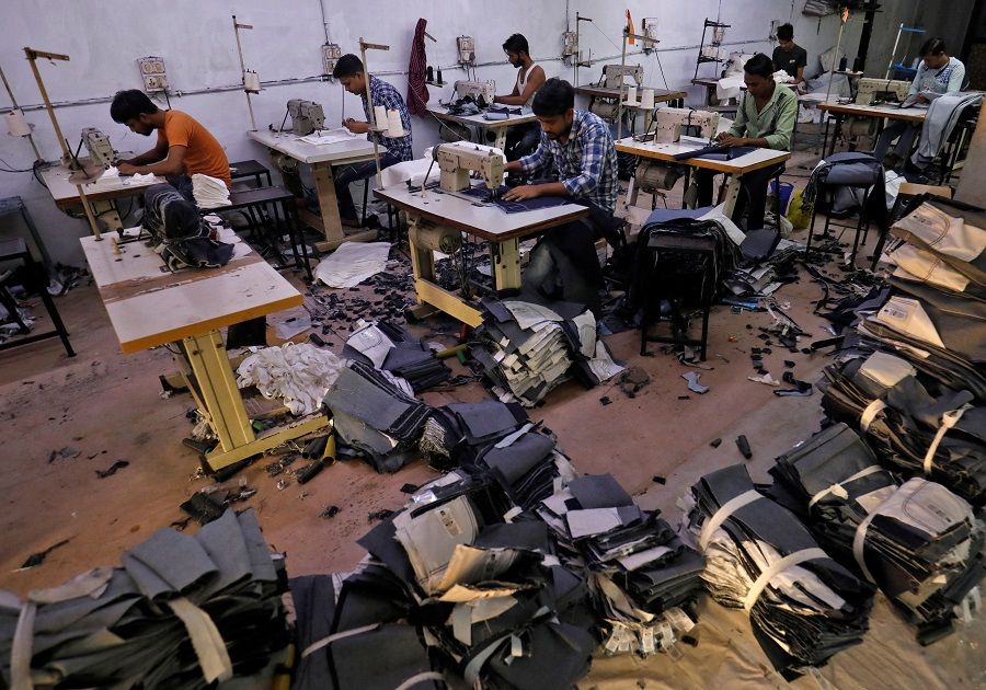 Workers sew jeans and cotton trousers in a garments manufacturing unit in Ahmedabad, India, 13 December 2022. (Amit Dave/Reuters)