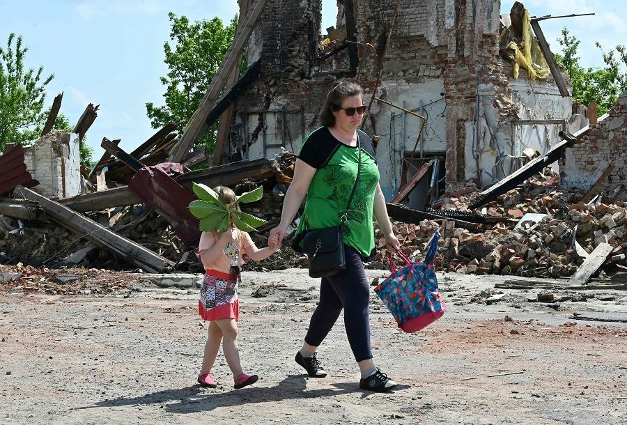 Local residents walk past a building destroyed by shelling in the centre of Kupiansk, Kharkiv region, Ukraine, on 26 May 2023, amid the Russian invasion of Ukraine. (Sergey Bobok/AFP)