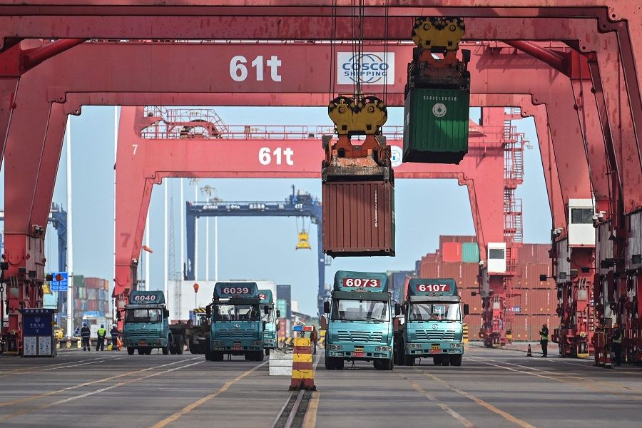 Cranes load containers on trucks at the Lianyungang Port Container Terminal in Lianyungang, Jiangsu province, China, 24 March 2021. (Hector Retamal/AFP)