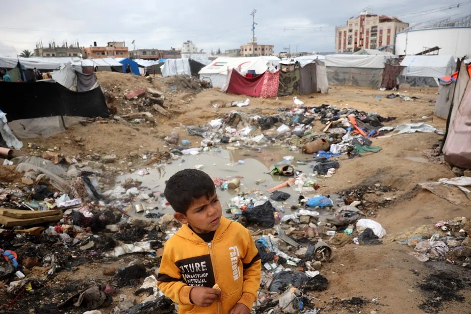 A Palestinian boy stands near rubbish and stagnant water at a camp for displaced people in Nuseirat in the central Gaza Strip on 23 February 2025. (Eyad Baba/AFP)