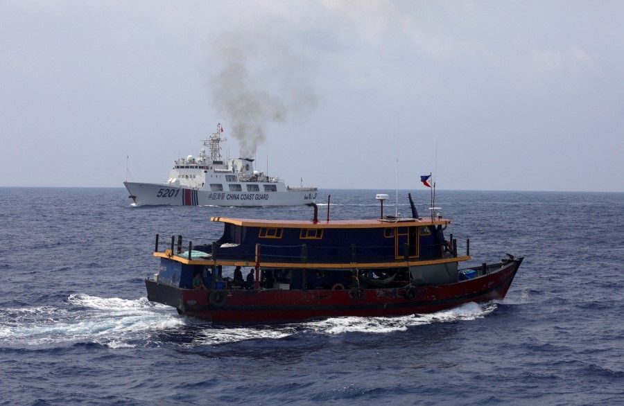 A Philippine supply boat sails near a Chinese Coast Guard ship during a resupply mission for Filipino troops stationed at a grounded warship in the South China Sea, on 4 October 2023. (Adrian Portugal/Reuters)