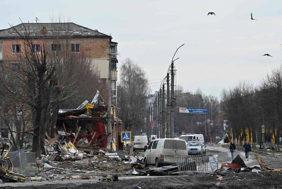 People walk among debris of destroyed cars and damaged buildings on a street in the town of Borodianka, northwest of Kyiv, on 6 April 2022, during Russia's military invasion launched on Ukraine. (Genya Savilov/AFP)