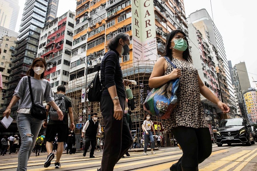 In this picture taken on 13 May 2022, people cross a street in Hong Kong. (Isaac Lawrence/AFP)