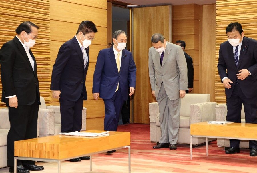 Japan's Prime Minister Yoshihide Suga (centre, blue suit) arrives to attend a cabinet meeting at the prime minister's office in Tokyo on 25 May 2021. (STR/Jiji Press/AFP)