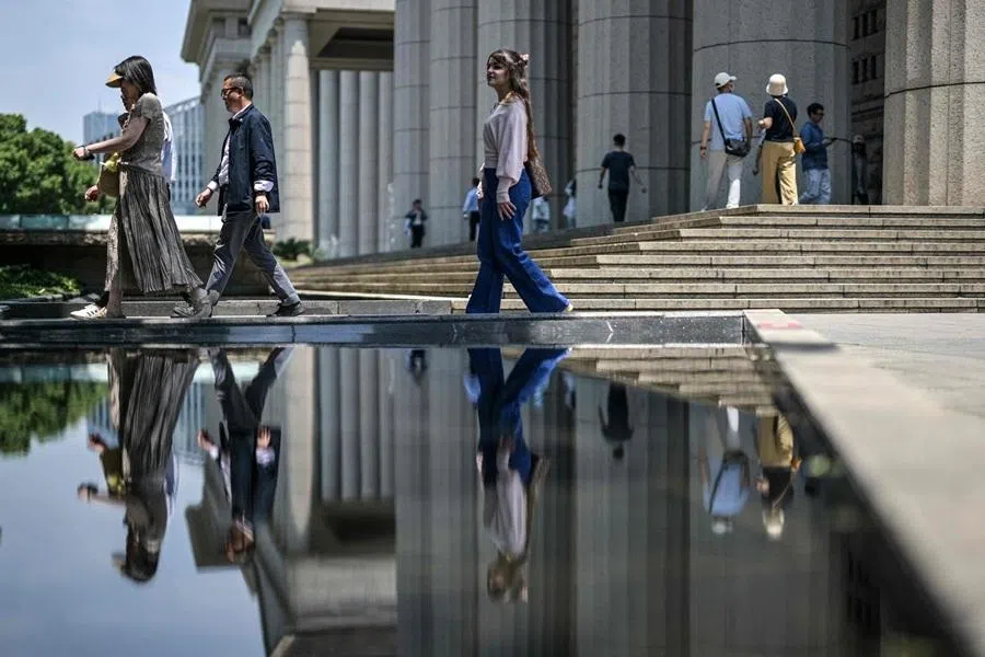 People walk next to a building at the financial district of Lujiazui in Shanghai on 1 June 2026.