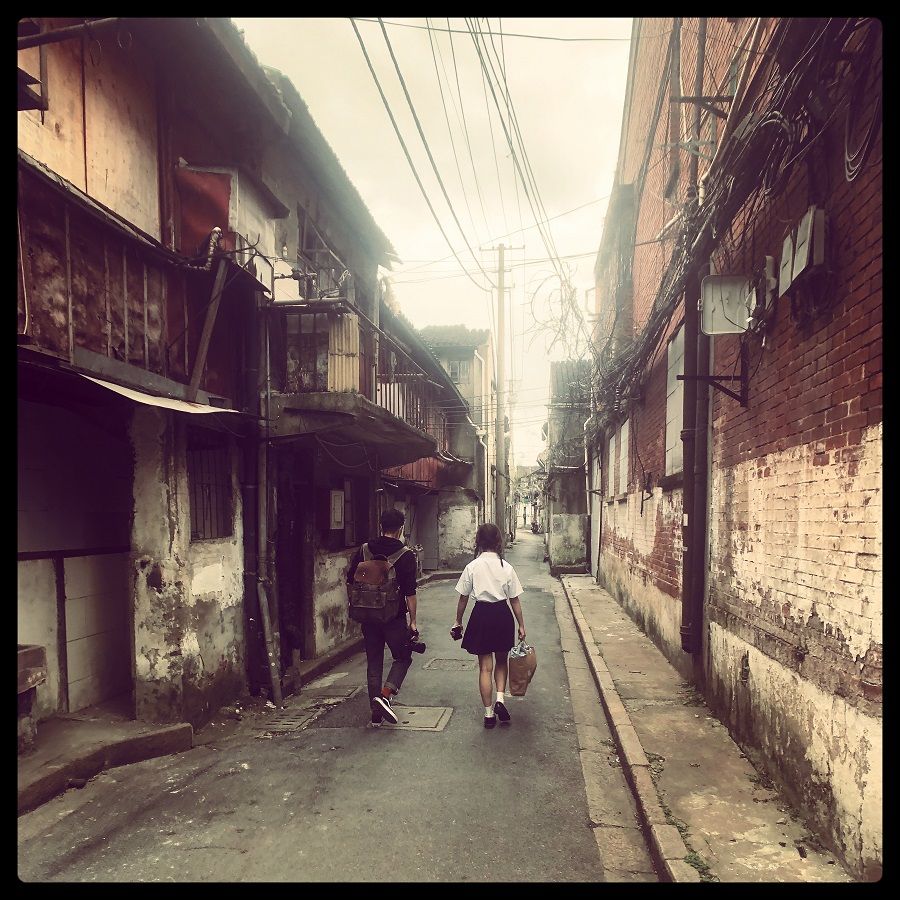 Boy and schoolgirl walk through a boarded-up neighbourhood in Laoximen.