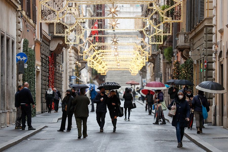 People wearing protective masks walk along Via dei Condotti street in Rome, Italy, 2 December 2020. (Yara Nardi/Reuters)