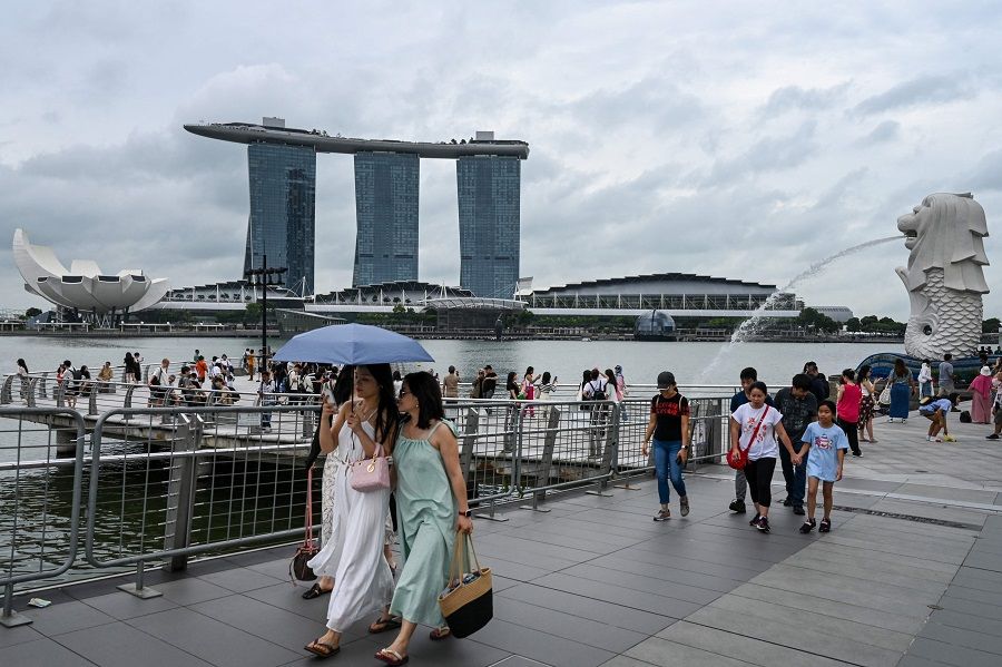 People walk past the Merlion statue with the backdrop of the Marina Bay waterfront in Singapore on 3 January 2024. (Roslan Rahman/AFP)