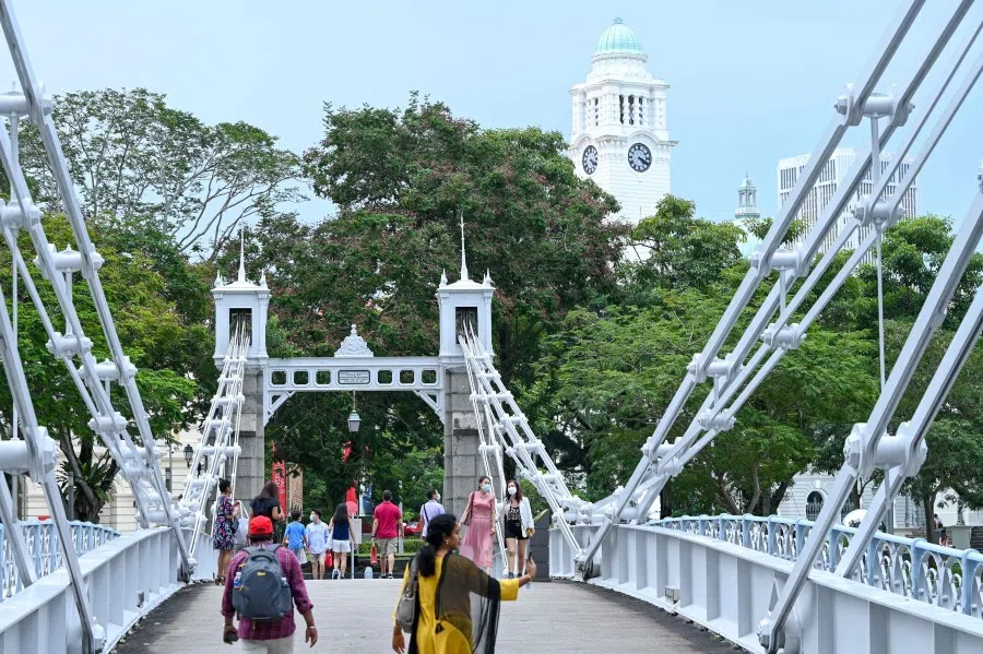 People walk across Cavenagh Bridge in Singapore on April 3, 2022. (Photo by Roslan RAHMAN / AFP)