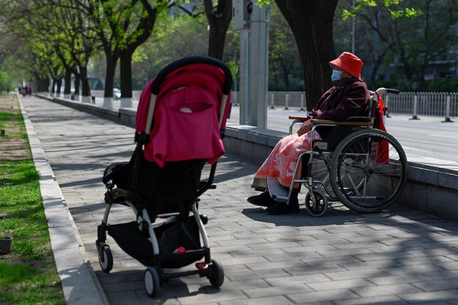 An elderly woman sits in her wheelchair on a sidewalk in Beijing on 19 April 2022. (Wang Zhao/AFP)