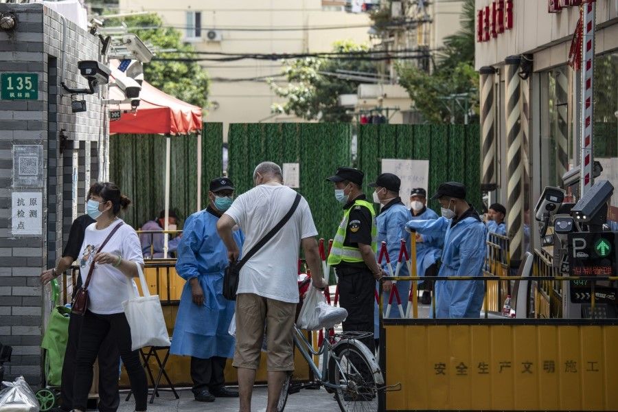 Workers in protective gear at an entrance to a residential neighbourhood placed under lockdown due to Covid-19 in Shanghai, China, on 6 July 2022. (Qilai Shen/Bloomberg)