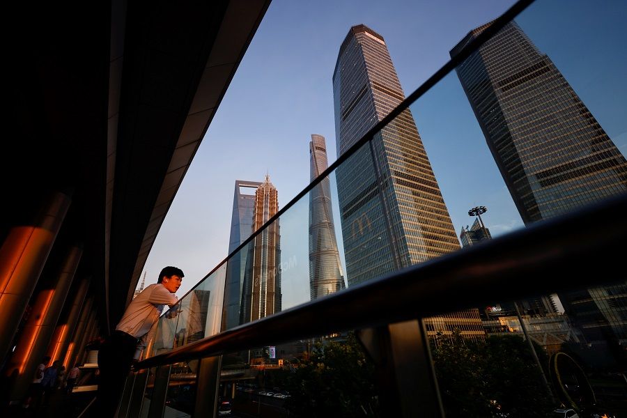 A man makes a call through the headset in the Lujiazui financial district during sunset in Pudong, Shanghai, China, 13 July 2021. (Aly Song/Reuters)