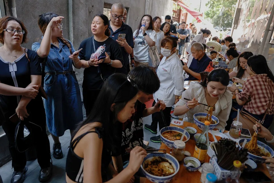 People queue beside customers eating at a restaurant in Shanghai, China, on 28 September 2024. (Tingshu Wang/Reuters)