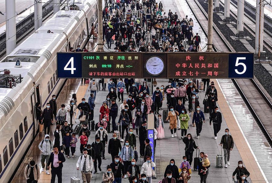 People arrive at Shenyang Railway Station in Liaoning, China, on 7 October 2020. (STR/AFP)