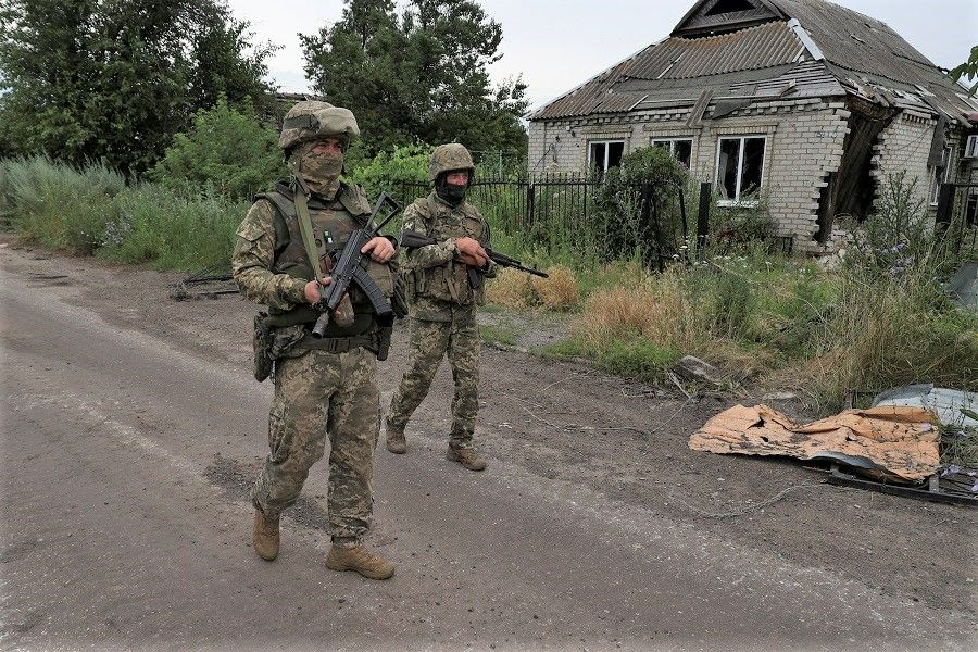 Ukrainian servicemen walk past a house damaged by a Russian military strike in the village of Vremivka, amid Russia's attack on Ukraine, near a front line in Donetsk region, Ukraine, 8 July 2023. (Sofiia Gatilova/Reuters)