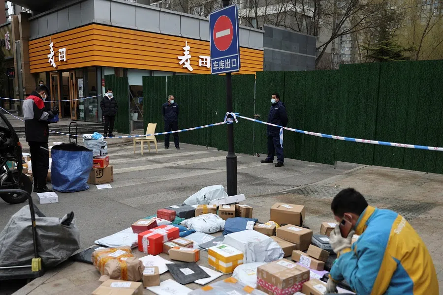 A delivery worker sorts parcels in Beijing, China, 17 March 2022. (Tingshu Wang/Reuters)