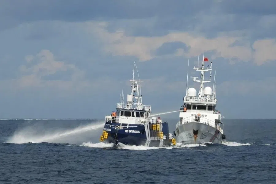 This handout photo taken and released on 12 October 2025 by the Philippine Coast Guard shows a China Coast Guard ship (right) deploying water cannon as a Philippine Bureau of Fisheries vessel (left) is seen alongside during an incident near Thitu island in disputed waters of the South China Sea. (Handout/Philippine Coast Guard (PCG)/AFP)