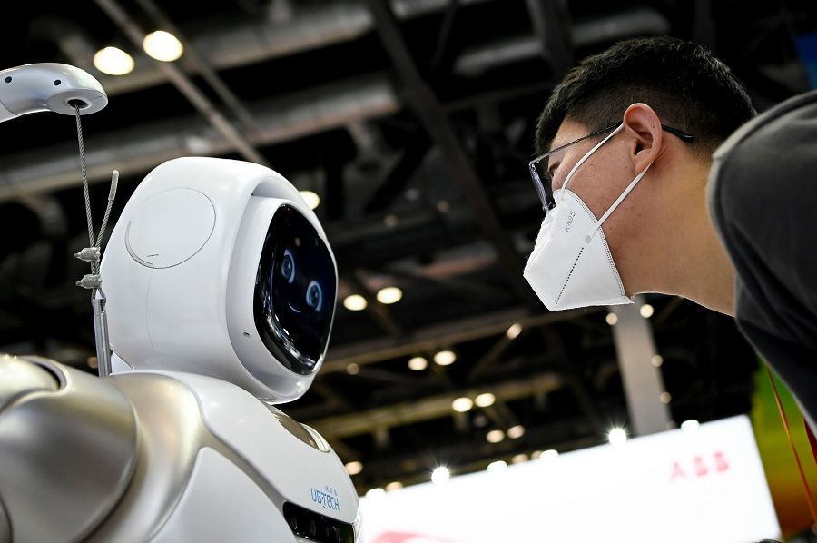 A man wearing a face mask looks at a robot at the China National Convention Centre, the venue for the upcoming the China International Fair for Trade in Services (CIFTIS) in Beijing on 3 September 2020. (Wang Zhao/AFP)