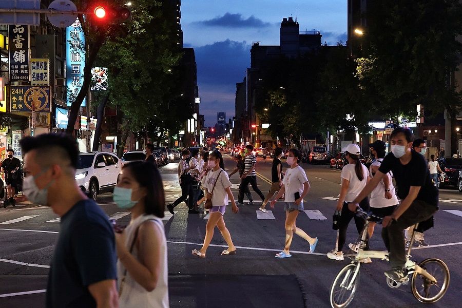 People wearing protective masks cross the road to the newly opened night market in Taipei, Taiwan, 2 July 2021. (Ann Wang/Reuters)