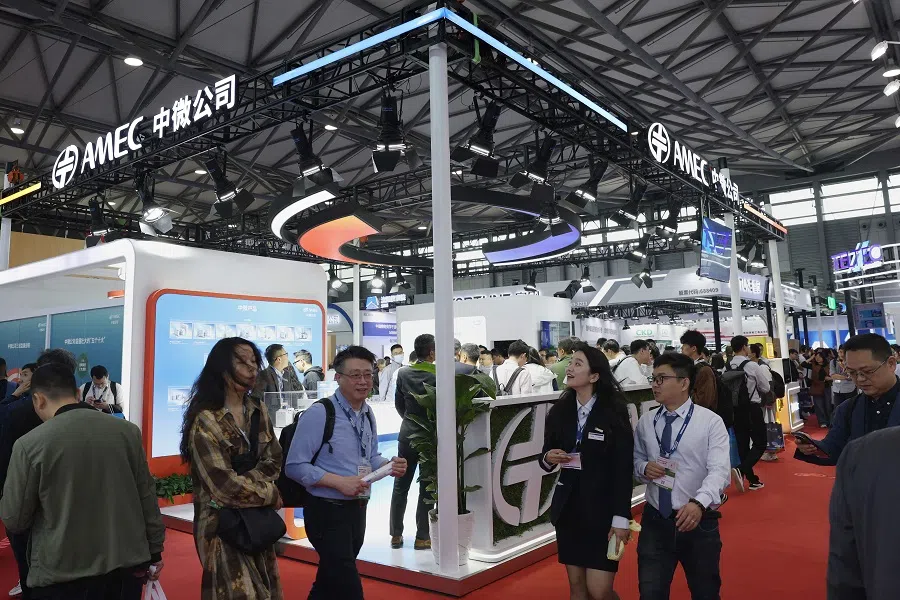 People walk through the AMEC (Advanced Micro-Fabrication Equipment) stand at the SEMICON China semiconductor exhibition in Shanghai, China, on 26 March 2025. (AFP)