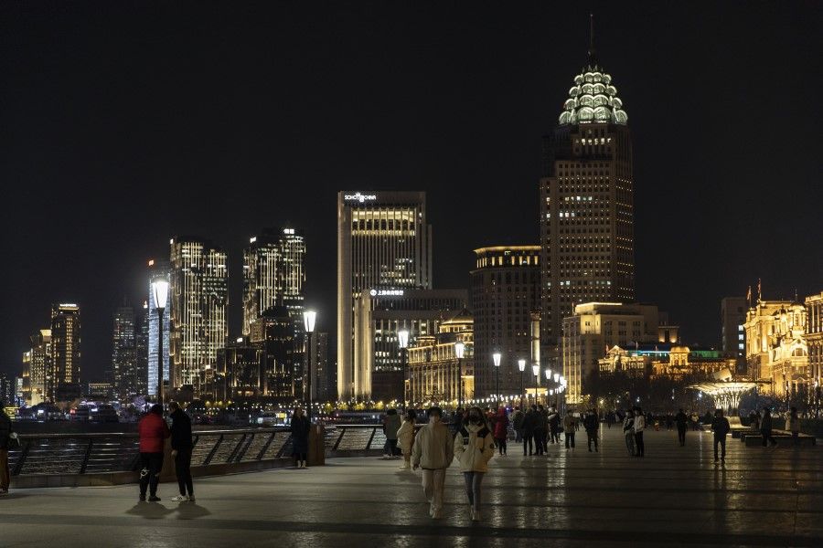 Pedestrians walk along the Bund past illuminated buildings at night in Shanghai, China, on 28 December 2021. (Qilai Shen/Bloomberg)